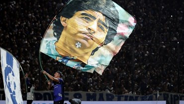 مشجع يرفع صورة لمارادونا قبل مباراة في دوري المحترفين الأرجنتيني لكرة القدم 2022 (أ ف ب).