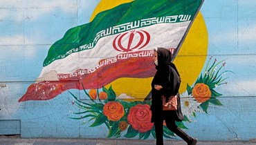 امرأة تمر قرب جدارية في طهران (11 ت1 2022، أ ف ب).