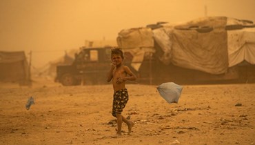 صبي يمشي في مخيم سهل البنات للنازحين في ريف الرقة شمال سوريا (17 ت1 2022، أ ف ب). 