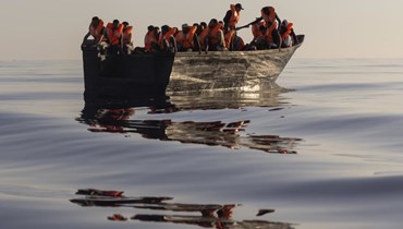 مهاجرون يرتدون سترات نجاة قدمها اليهم متطوعون في سفينة اوشن فايكينغ، يبحرون في قارب خشبي خلال إنقاذهم (27 آب 2022، أ ب). 