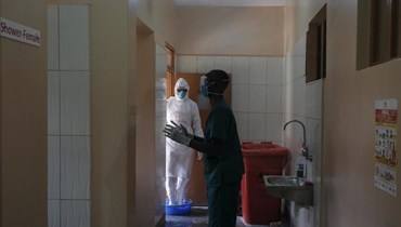أطباء يطهرون أنفسهم بعد زيارة مريض كان على اتصال بأحد  ضحايا الإيبولا، في قسم العزل في مستشفى عنتيبي بعنتيبي في أوغندا (20 ت1 2022، أ ب). 