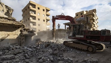 عمال سوريون يجمعون قضبان الصلب من أنقاض ابنية مدمرة في مدينة الرقة الشمالية (15 ت1 2022، أ ف ب). 