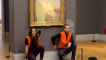 الناشطان المناخيان أمام لوحة "الرحى" للرسام الفرنسي كلود مونيه في متحف باربريني وقد غطّتها البطاطا المهروسة (24 ت1 2022 - أ ف ب).
