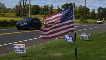  تمر السيارات عبر العشب الأمامي مع علامات الحملة السياسية للمرشحين الجمهوريين بالقرب من بنسلفانيا (أ ف ب). 