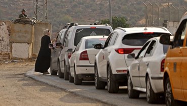 فلسطينيون ينتظرون في طابور طويل عند نقطة تفتيش إسرائيلية بين مدينة نابلس الفلسطينية وقرية بيت فوريك في الضفة الغربية المحتلة (26 ت1 2022، أ ف ب).