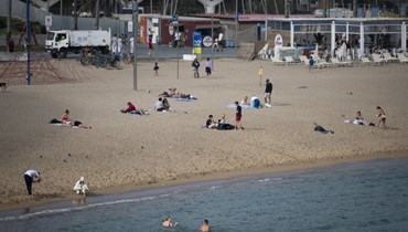 اشخاص استراحوا على شاطئ برشلونيتا في برشلونة (27 ت1 2022، أ ف ب).
