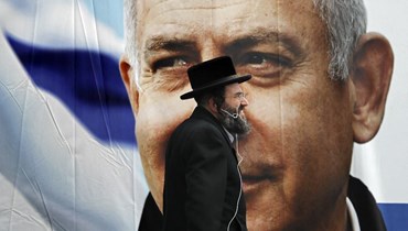 صورة ارشيفية- رجل يهودي أرثوذكسي متشدد يمر أمام لوحة إعلانية انتخابية كبيرة لنتنياهو في القدس (1 نيسان 2019/ أ ف ب).