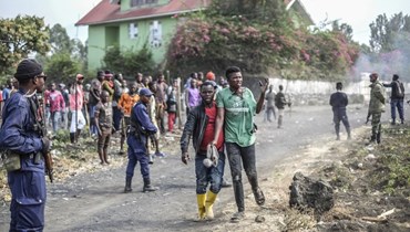 صورة تعبيرية- متظاهر مصاب يمر قرب شرطيين خلال احتجاج في ساكي على قوة "مونوسكو" المنتشرة في جمهورية الكونغو الديموقراطية (27 تموز 2022/ أ ب). 