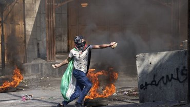 متظاهر فلسطيني يرشق الحجارة خلال اشتباكات مع قوات الأمن الإسرائيلية في وسط مدينة الخليل بالضفة الغربية المحتلة (30 ت1 2022، أ ف ب).