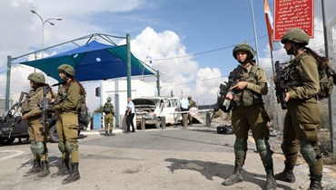 جنود إسرائيليون يقفون قرب سيارة تضررت في عملية دهس عند حاجز بيل في جوار مستوطنة بيت حورون في الضفة الغربية المحتلة (2 ت2 2022، أ ف ب). 