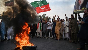 أنصار خان يرددون هتافات قرب إطارات مشتعلة خلال إغلاقهم الطريق السريع الرئيسي في موقع الهجوم في وزير أباد (4 ت2 2022، أ ف ب). 
