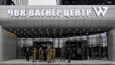اشخاص يرتدون ملابس عسكرية مموهة وقفوا عند مدخل 'PMC Wagner Center'، خلال الافتتاح الرسمي للمكتب في سانت بطرسبرج (4 ت2 2022، أ ف ب). 