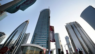 أشخاص يمرون قرب لافتات للفيفا في الدوحة، قبل مونديال 2022 (7 ت2 2022، أ ف ب).