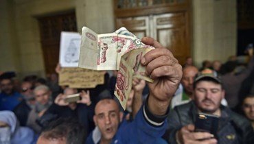 رجلٌ يلوّح بأوراق نقديّة أمام محكمة في العاصمة الجزائر بتاريخ 2 كانون الأول 2019 ( ا ف ب / رياض كرمدي)