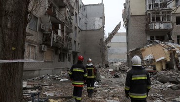 عمال إنقاذ انتشروا قرب مبنى سكني متضرر من جراء قصف في ميكولايف (11 ت2 2022، أ ف ب). 