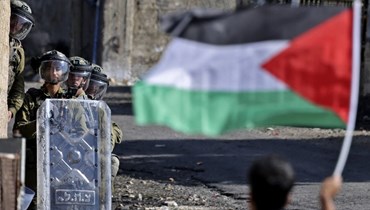 العلم الفلسطيني مقابل عدد من الجنود الإسرائيليين (أ ف ب).