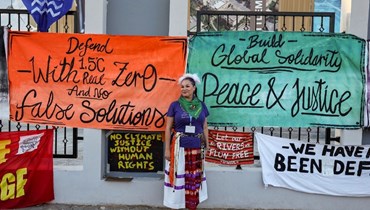 ناشطة تقف لالتقاط صورة خلال مظاهرة تطالب بالالتزام بالحد من ارتفاع درجة الحرارة العالميةخلال مؤتمر المناخ COP27 (أ ف ب). 