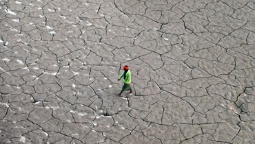 رجل يسير على طول مجرى جاف على ضفاف الغانج، في براياغراج (14 ت2 2022 - أ ف ب).