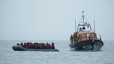 صورة ارشيفية- قارب تابع للمؤسسة الملكية الوطنية لقوارب النجاة يساعد مهاجرين قبل نقلهم إلى شاطئ في دانجينس على الساحل الجنوبي الشرقي لإنجلترا بعد عبورهم القناة الإنكليزية (124 ت2 2021، أ ف ب). 