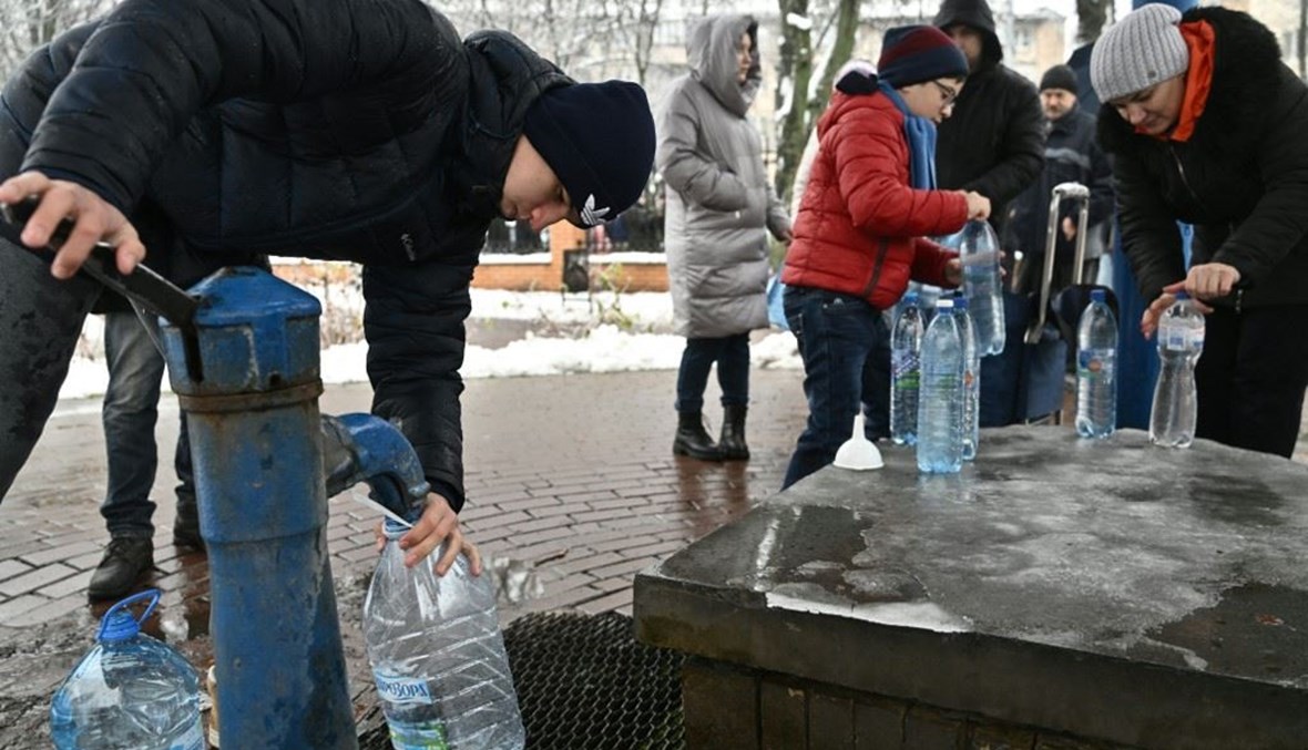 سكان يملأون زجاجات بلاستيكية بالماء من مضخة ماء في حديقة في كييف (24 ت2 2022، أ ف ب). 