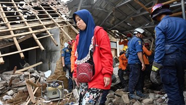 إيماس ماسفاهيتاه تنتظر بينما يعمل رجال إنقاذ للعثور على طفلها المفقود الذي يُعتقد أنه محاصر تحت أنقاض منزل منهار في كوجينانغ في سيانجور بجاوة الغربية (24 ت2 2022، أ ف ب). 