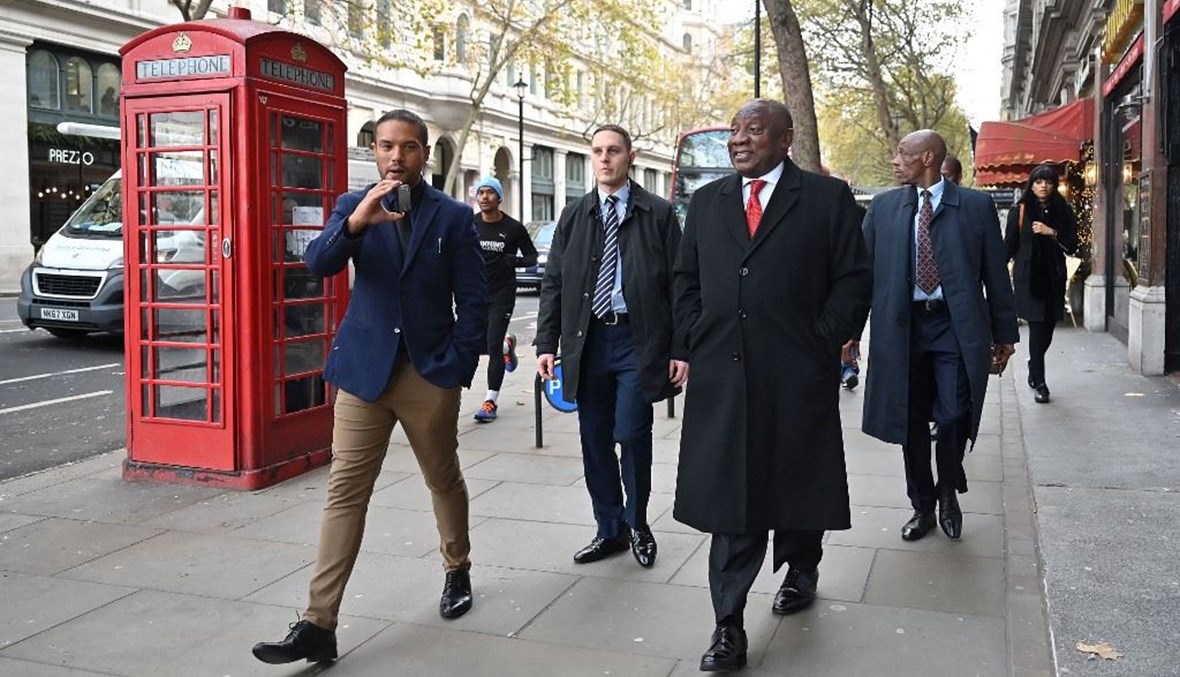 رامافوزا (في الوسط) يمشي قرب ميدان ترافالغار في وسط لندن قبل أن يتكلم في مؤتمر صحافي (24 ت2 2022، أ ف ب). 