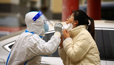عامل صحي يأخذ عينة لفحصها للكشف عن فيروس كورونا في جيايوغوان بمقاطعة قانسو شمال غرب الصين (24 ت2 2022 - أ ف ب).