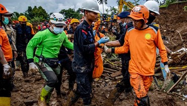 عمال إنقاذ يحملون جثة انتشلت من تحت الأنقاض في قرية كوجينانغ في سيانجور بجاوا الغربية (26 ت2 2022، أ ف ب). 
