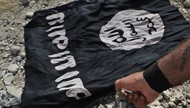 مقاتل من الميليشيات المسيحية السريانية التي تقاتل تنظيم الدولة الإسلامية تحت راية قوات سوريا الديموقراطية المدعومة من الولايات المتحدة، يحرق علم داعش على خط الجبهة عند الجانب الغربي من الرقة شمال شرق سوريا (17 تموز 2017، أ ب). 
