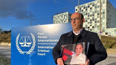 غسان بنات يحمل صورة لشقيقه نزار بنات خارج مقر المحكمة الجنائية الدولية في لاهاي، بعد رفع الدعوى القضائية (15 ك1 2022، أ ف ب). 