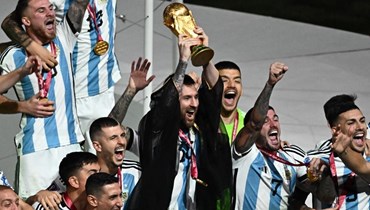 ليونيل ميسي يرفع كأس العالم بالبشت القطري (أ ف ب).