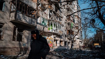 شخص يمر قرب مبنى سكني تضرر من القصف الروسي في خيرسون (20 ك1 2022، أ ف ب).