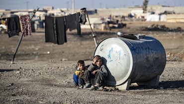 طفلان يجلسان بجانب خزّان في مخيّم شمال سوريا (أ ف ب). 