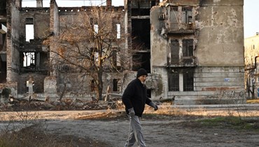 أحد السكان يمر قرب مبنى مدمر في بلدة ليمان بمنطقة دونيتسك (14 ك1 2022، أ ف ب).