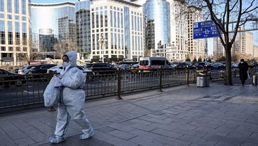  امرأة ترتدي معدّات الوقاية الشخصية وسط تفشي كوفيد، تمشي في أحد شوارع بيجينغ (أ ف ب). 