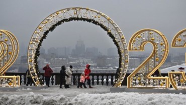 اشخاص يمرون بجانب مجسّم مكوّن من أرقام العام الجديد 2023 على تلال فوروبيوفي في موسكو (22 ك1 2022، أ ف ب).