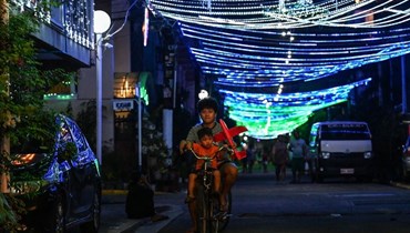 امرأة وطفل يركبان دراجة في شارع في مانيلا (21 ك1 2022، أ ف ب).