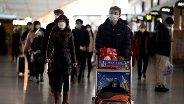 مسافرون يعبرون قاعة المغادرة في مطار بيجينغ الدولي (29 ك1 2022، أ ف ب). 