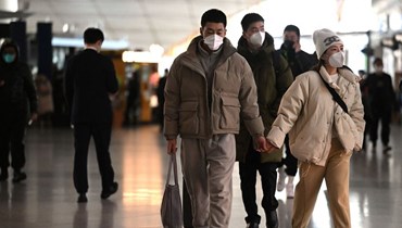مسافرون يعبرون قاعة المغادرة في مطار بيجينغ الدولي (29 ك1 2022، أ ف ب). 