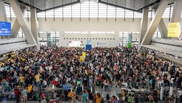 ركاب ينتظرون معلومات عن رحلاتهم في المبنى الرقم 3 في مطار نينوي أكينو الدولي في باساي بمترو مانيلا (1 ك2 2023، أ ف ب). 