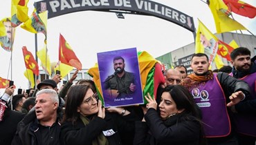 أفراد من الجالية الكردية يحملون نعشًا ملفوفًا بالعلم لواحد من ضحايا إطلاق النار، خلال تشييع في ضاحية فيلييه-لو-بيل بضواحي باريس (3 ك2 2023، أ ف ب). 