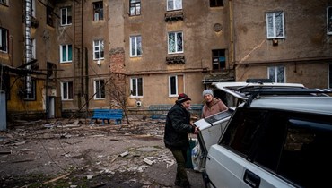 سكان محليون يحمّلون سيارتهم بمتعلقاتهم بجوار مبنى سكني مدمر في شاسيف يار شرق أوكرانيا (5 ك2 2023، أ ف ب). 