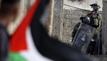 العلم الفلسطيني مقابل جنديّ إسرائيلي (أ ف ب).
