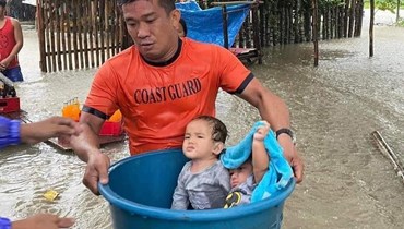  صورة التقطها خفر السواحل الفيلبيني لعمال الإنقاذ وهم يقومون بإجلاء الأطفال من منطقة غمرتها الفيضانات (أ ف ب).