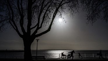 رجل يجلس تحت أشعة الشمس في موقع يطل على البحر في سان نازير غرب فرنسا (11 ك2 2023، أ ف ب).