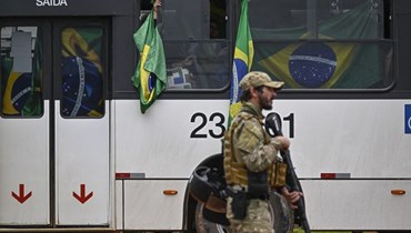 موقوفون من أنصار بولسونارو لدى نقلهم في حافلات إلى مقر الشرطة الفيدرالية في برازيليا بعد اعمال الشغب (9 ك2 2023، أ ف ب). 