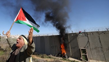 فلسطيني يرفع علم بلاده خلال تحرّك عند الجدار الفاصل (أ ف ب).