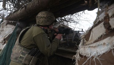 جندي أوكراني يوجه رشاشه باتجاه موقع روسي على خط المواجهة في منطقة دونيتسك (23 ك2 2023، أ ف ب). 