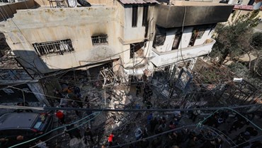 أشخاص تجمعوا حول مبنى دمرته القوات الإسرائيلية خلال مداهمة مخيم جنين للاجئين في الضفة الغربية (26 ك2 2023، أ ف ب). 