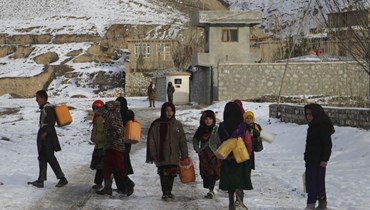  أطفال يحملون حاويات لجلب مياه الشرب خلال يوم بارد في منطقة يافتال سوفلا بمقاطعة بدخشان (أ ف ب). 